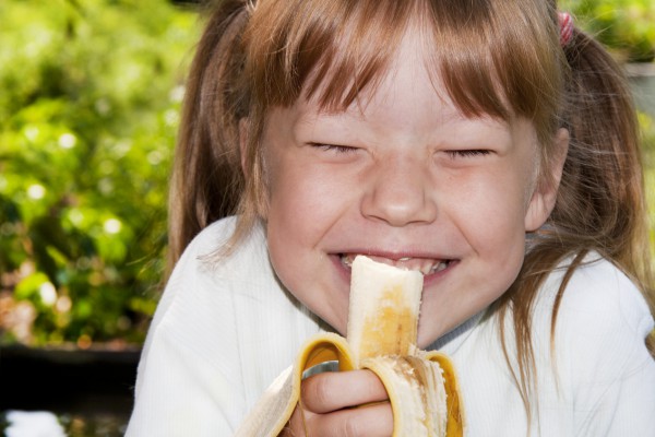 Девочка ест банан