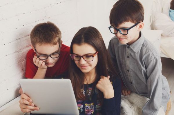 Дети в очках сидят за планшетом