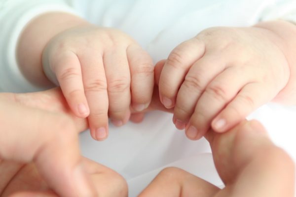 Малыш держится за мамины пальцы