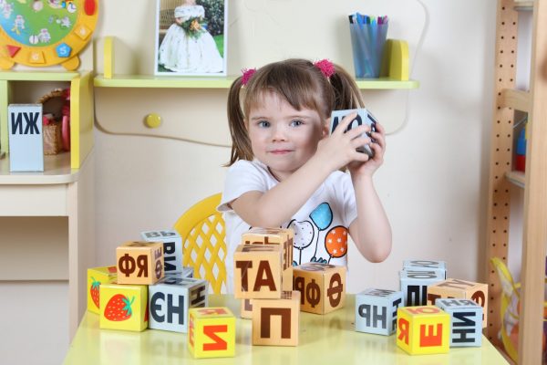 Девочка учит буквы по кубикам