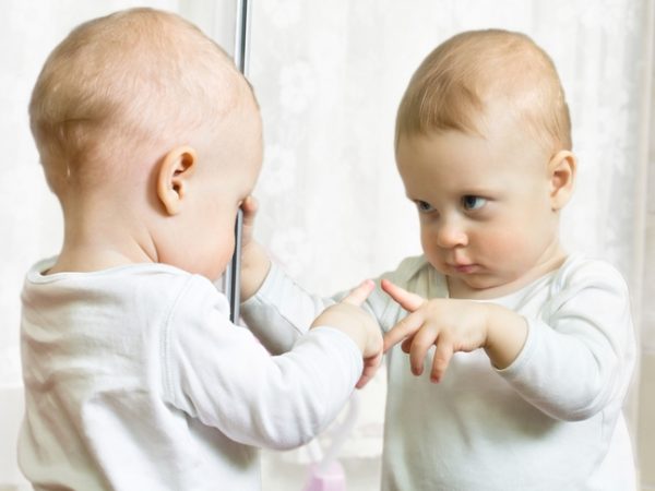 Малыш разглядывает себя в зеркале