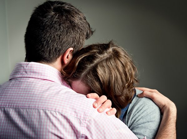 Женщина плачет на плече мужа