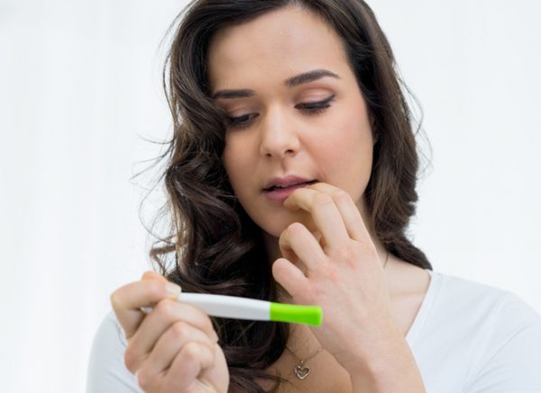 Женщина смотрит на тест на беременность