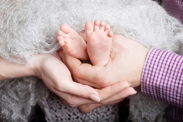 Детские ножки в руках родителей