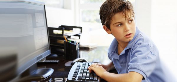 Мальчик оглядывается, сидя за компьютером